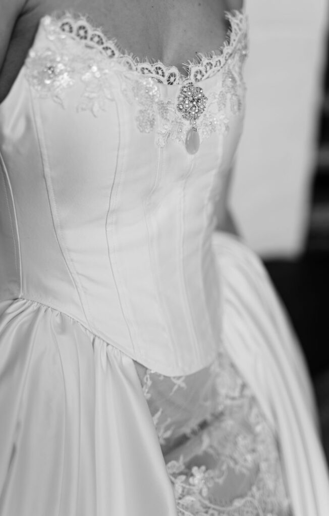 Schwarz-Weiß-Aufnahme einer Brautkleid-Corsage mit Spitzenkante und Spitzenapplikationen am Rock